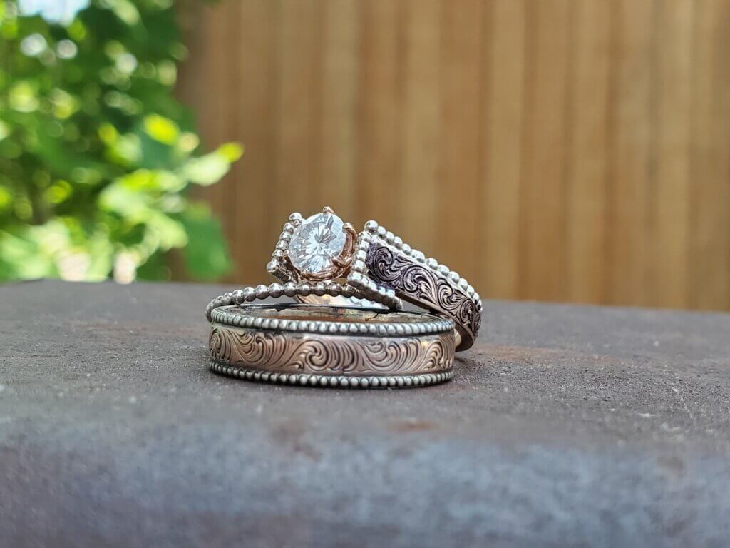 A lovely rose gold and sterling silver wedding ring set sits outside. 