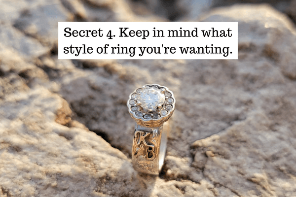 A beautiful engraved ring with a flower-like center setting is propped up on a rock. 