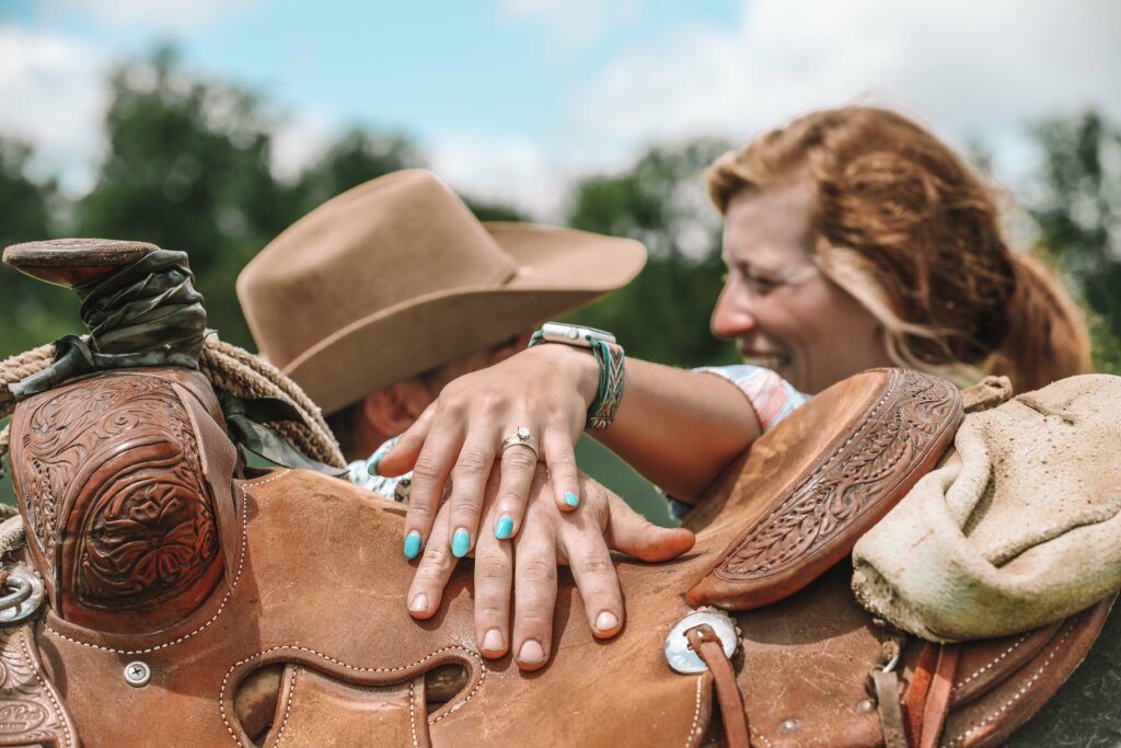 A woman shows off her new custom engagement ring on a saddle. 