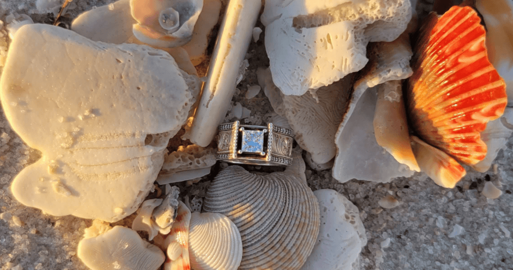 A sterling silver western engagement ring sits in a pile of sea shells.